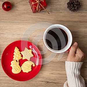 Merry Christmas with woman hand holding coffee cup and homemade cookie on table. Xmas eve, party, holiday and happy New Year