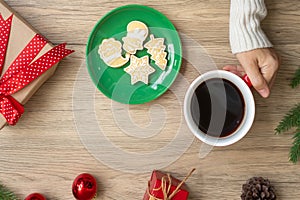 Merry Christmas with woman hand holding coffee cup and homemade cookie on table. Xmas eve, party, holiday and happy New Year