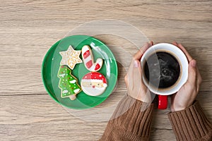 Merry Christmas with woman hand holding coffee cup and homemade cookie on table. Xmas eve, party, holiday and happy New Year