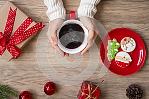 Merry Christmas with woman hand holding coffee cup and homemade cookie on table. Xmas eve, party, holiday and happy New Year