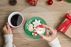 Merry Christmas with woman hand holding coffee cup and homemade cookie on table. Xmas eve, party, holiday and happy New Year