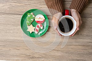 Merry Christmas with woman hand holding coffee cup and homemade cookie on table. Xmas eve, party, holiday and happy New Year