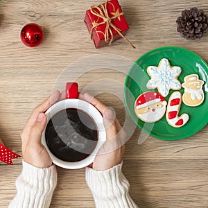 Merry Christmas with woman hand holding coffee cup and homemade cookie on table. Xmas eve, party, holiday and happy New Year