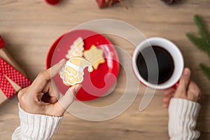 Merry Christmas with woman hand holding coffee cup and homemade cookie on table. Xmas eve, party, holiday and happy New Year