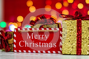 Merry Christmas wooden sign and glittery Christmas gifts. Christmas composition on blurred lights background