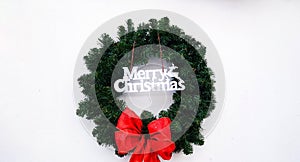 Merry Christmas wreath with green leaves and red ribbon isolated on white background with copy space.