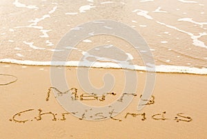 Merry Christmas written in sand on beach
