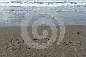 Merry Christmas written in the sand with wet sand behind