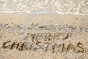Merry Christmas written on tropical beach sand, copy space.