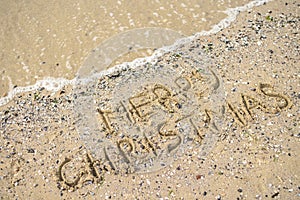 Merry Christmas written on tropical beach sand, copy space.