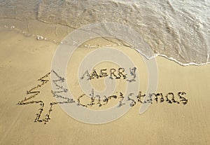 Merry Christmas written on tropical beach white sand with snowman
