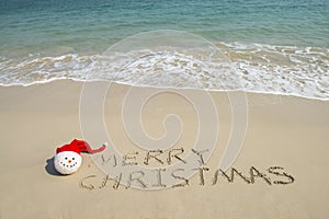 Merry Christmas written on tropical beach white sand with snowman