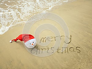 Merry Christmas written on tropical beach white sand with snowman