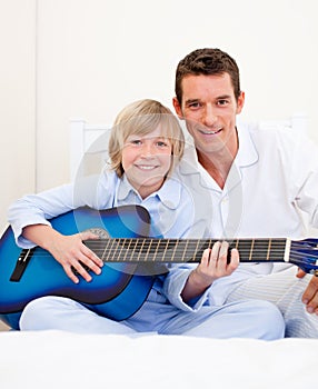 Merry little boy playing guitar with his father