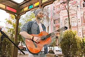 Merry male guitarist divvying music on street