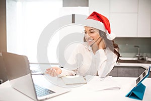 Merry New Year and Merry Christmas. Beautiful black-haired woman works from home. An employee sits in the kitchen and