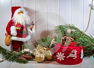 Merry New Year mood. Santa Claus doll, New Year`s decor, branches of a Christmas tree and a gift in a red box.