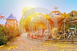 Merry-round-go Horse Carousel in Autumn park. Fall landscape wit