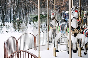 Merry-round-go Horse Carousel in winter park. Winter snow landscape with Retro carousel roundabout white horse. Off