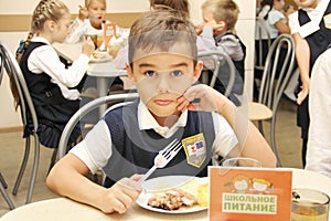 Merry schoolboy Sitting At Table In School Cafeteria Eating Meal. drinking juice - Russia, Moscow, the first High School, the firs