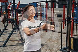 Merry senior woman training with cables outdoors