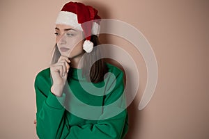 Merry surprised young woman wear xmas sweater Santa hat posing pointing hands arms aside indicate on workspace area isolated on