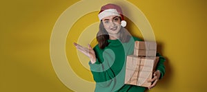 Merry surprised young woman wear xmas sweater Santa hat posing pointing hands arms aside indicate on workspace area isolated on