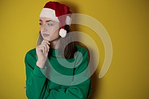 Merry surprised young woman wear xmas sweater Santa hat posing pointing hands arms aside indicate on workspace area isolated on