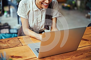 Merry young lady with cornrows working on her laptop