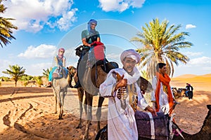 MERZOUGA, MOROCCO - August 02: A Berber male guide in traditional dress training a young male camel in the Erg Chebbi