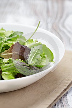 Mesclun mix salad in white bowl