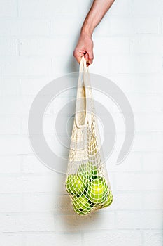 Mesh bag with apples in male hand.