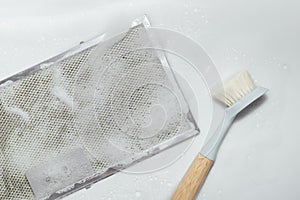 Mesh filter of cooker hood with brush and foam, white background