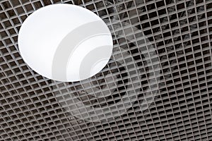 Mesh suspended ceiling with fluorescent or LED round lights in a modern shopping center or office building