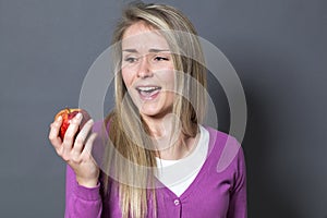 Mesmerized 20s girl not resisting in eating appetizing apple