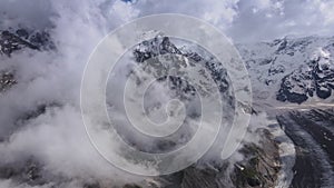 Mesmerizing aerial view of a mountain gorge with swirling clouds and glacier