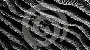 Black and white sand texture with wavy ridges and grooves, resembling wind-formed dunes photo