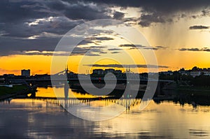 Mesmerizing blazing sunset over the mirror glossy surface of the Volga river, reflecting dramatic sky. City of Tver, Russia.