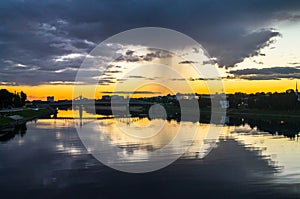 Mesmerizing blazing sunset over the mirror glossy surface of the Volga river, reflecting dramatic sky. City of Tver, Russia.