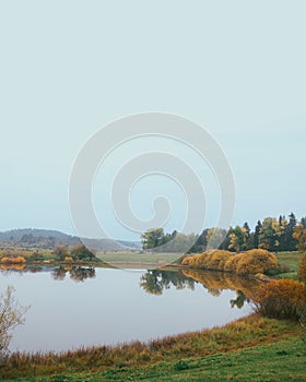 Mesmerizing circular lake surrounded by bushes and trees in fall colors, autumn foliage