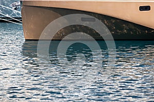 The mesmerizing reflection of the water on the glossy side of a huge yacht anchored, chrome details