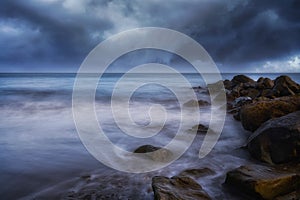 Mesmerizing seascape with wavy water and rocky coast on the gloomy sky background