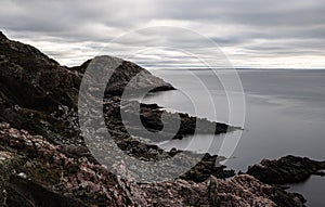 Mesmerizing view of a rocky shore and a calm sea on a gloomy day