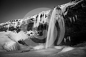 Mesmerizing winter scene of a picturesque waterfall cascading down a rocky mountainside