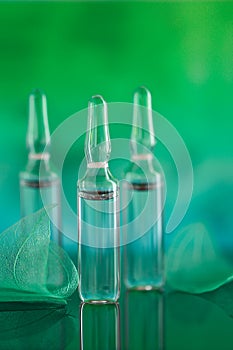 Mesotherapy and dermabrasion serum in ampoules. cosmetic ampoules.Beauty product.Transparent ampoules and green photo