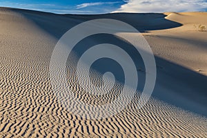 Mesquite Sand Dunes, Death Valley, California. Rippled pattern in the sand. Blue sky and clouds in distance.