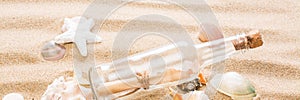 Message in bottle on the beach.  Summer background with hot sand, for banner