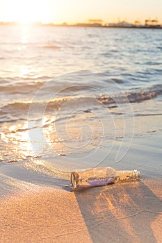 Message in a bottle on beach with sunset and blur industry background