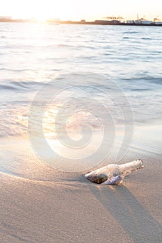 Message in bottle on beach with sunset and blur industry background