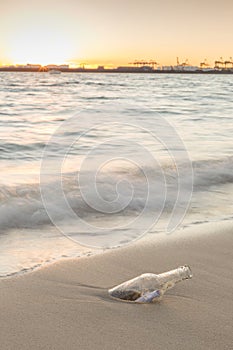 Message in bottle on beach with sunset and blur industry background